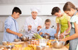 © JackF - At culinary master class, experienced female chef in white uniform explains subtleties of dessert preparation to children. Woman shows sequence of actions during cooking