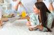© Pixel-Shot - Young woman with coffee and her boyfriend having breakfast in bedroom