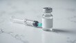 © Ornpitchayawee - Vaccine vial with syringe on marble background in a clinical setting, showcasing medical equipment and health care concepts for vaccination