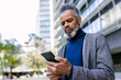 © Westend61 - Mature businessman using smart phone in front of building