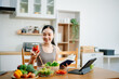 © laddawan - Female athete in sportswear standing in kitchen in sportswear and writing down healthy recipe. Active healthy lifestyle, clean eating