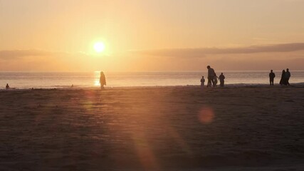 Wall Mural - golden sunlight bathing sandy coastline, tourists leisurely walking along picturesque portuguese bea