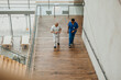 © Maskot - High angle view of male physicians wearing medical scrubs talking with each other while moving up steps in hospital buil
