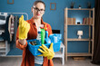 © Andrii Lysenko - young woman with basket of detergent products showing beckoning gesture with fingers, looking at camera. Cleaning and housework