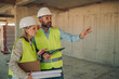 © Zamrznuti tonovi - Construction workers discussing blueprint plans on building site