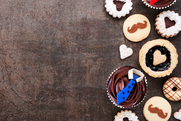 Leinwandbilder - Fathers Day themed baking side border with an assortment of cookies and sweet treats. Top down view on a dark stone background with copy space.