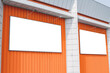 © Victor - Two Blank banner or billboard mockups on the orange wall of a building. Street advertising on the screen of the city.