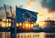 © kestrel - EU flag flying in front of an industrial port at sunset The American flag is centered and waving with the sun setting behind it creating long shadows on cranes and silhouettes again