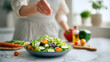 © Riverruno - Woman salting tasty salad at white marble table indoors, closeup