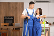 © Pixel-Shot - Cute young couple with vacuum cleaner and floor mop in kitchen