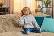 © Andrii Iemelianenko - Young teenager girl waving hand with happy smile at home, expressing joy and friendliness. Caucasian child kid sitting on a sofa, saying hello hi welcome or goodbye with cheerful and relaxed attitude