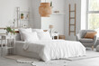 © Pixel-Shot - Interior of bedroom with cozy bed, grey armchair, houseplants and bedside tables
