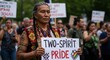 © velikiyzayats - Middle-aged Indigenous person with facial tattoos and traditional clothing holds a 'TWO-SPIRIT PRIDE' sign during a protest or march.