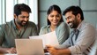 © Jo - Indian Coworkers Smiling While Reviewing Project Together Indoors