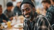 © vetrana - Homeless black man engaging at shelter dining table with diverse group in uplifting environment