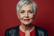 © People's Stock's - A gracefully aging woman with short silver hair poses against a vibrant red background