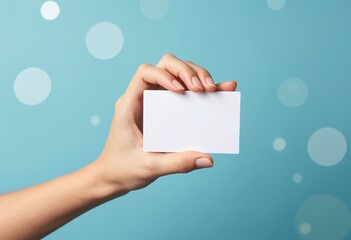 Fototapete - A hand holds a blank white card against a blue background with soft circular light effects