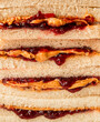 © Cavan Images - Close up of stack of peanut butter and jam sandwiches on white bread.