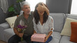 © Krakenimages.com - Man covering woman's eyes while sitting in cozy living room, offering flowers with her holding gift, portraying joyful middle age indoor family love.