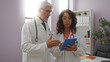 © Krakenimages.com - Woman doctor and man doctor discussing medical information on tablet in hospital room with shelves and plants.