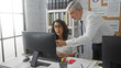 © Krakenimages.com - Man and woman collaborating at a desk in a bright office, focused on a computer screen with files and documents, showcasing teamwork in a modern workspace setting.