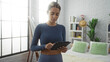 © Krakenimages.com - Young woman using tablet in bright modern bedroom with white brick walls and minimalist decor denotes a relaxed and contemporary lifestyle indoors.