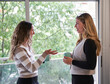 © Marc Elias - Two women talking and drinking coffee during an office break by the window