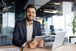 © Liubomir - Portrait of a successful young businessman, the man is smiling and looking at the camera. The company employee in a business suit is holding a tablet computer and a laptop in his hands.