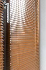 Fototapete - Wooden blinds close-up partially closed on a window, with sunlight filtering through the horizontal slats. The warm tone of the wood contrasts with the metal window handle and the smooth white wall.
