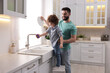 © New Africa - Father and his son washing dishes together in kitchen at home