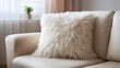 © Suphawan - Blank, fluffy pillow on a cream-colored sofa, perfect for lounging or curling up with a good book