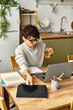 © LIGHTFIELD STUDIOS - Young stylish man working on laptop at modern kitchen table while enjoying a drink