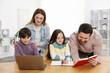 © New Africa - Parents helping their kids with homework at wooden table indoors