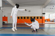 © o_lypa - Female fencers making simultaneous epee hit in indoor duel.