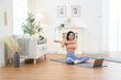 © tonefotografia - Woman Practicing Yoga at Home in a Serene Living Room With a Laptop and a Dog Nearby