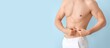 © Pixel-Shot - Young man touching his belly fat on light blue background with space for text, closeup. Plastic surgery concept