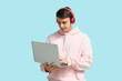 © Pixel-Shot - Handsome young man with headphones and laptop on blue background