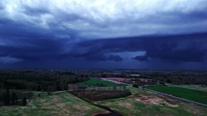 Wall Mural - dark clouds and lightning over rural fields and forests. aerial wide shot