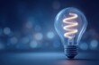 © AiHRG Design - A clear light bulb with a spiral filament emits a warm glow. It stands on a smooth surface, surrounded by a blurred blue background, creating a calming nighttime atmosphere.