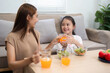 © wichayada - Wellness through healthy drinking: Mother and daughter sharing juice