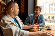 © we.bond.creations - Two male friends are catching up over coffee in a cozy cafe, engaging in lively conversation and enjoying each other's company