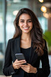 © Shivani - businesswoman in black blazer holding smartphone and smiling