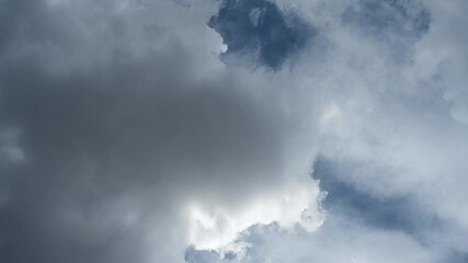 Wall Mural - Time-lapse of white to gray summer clouds drifting across a sky with blue patches
