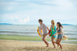 © Wanwajee - Carefree beach adventure with friends! Trio running in excitement with colorful tubes, surrounded by sea breeze and sunny vibes.