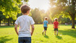 © iZlata - Boy observing his friends playing outdoors in a sunny park
