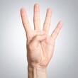 © Simon - Caucasian adult hand showing number four gesture on gray background