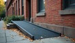 © miss irine - Wheelchair ramp leads building entrance. Autumn scene features fallen leaves. Ramps provide accessibility for people mobility. Red brick building backdrop, sidewalk. Symbol inclusion, accommodation.