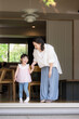 © kapinon - 庭先や軒先がある部屋でくつろぐ手を繋ぐ母親と娘（子供）子育ての幸せのイメージ