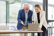 © David - Businessman and Woman Working Together on Laptop in Contemporary Office.Successful Team Meeting with Digital Device in Stylish Office Setting