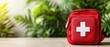 © RUENGWILAI - A red first aid kit with a white cross sits ready for emergencies on a wooden surface outdoors.